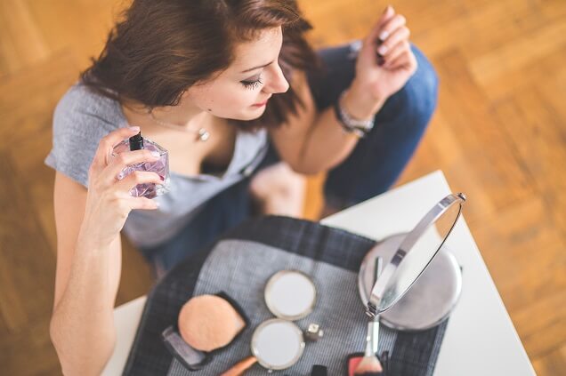 Woman in front of mirror with perfume and makeup