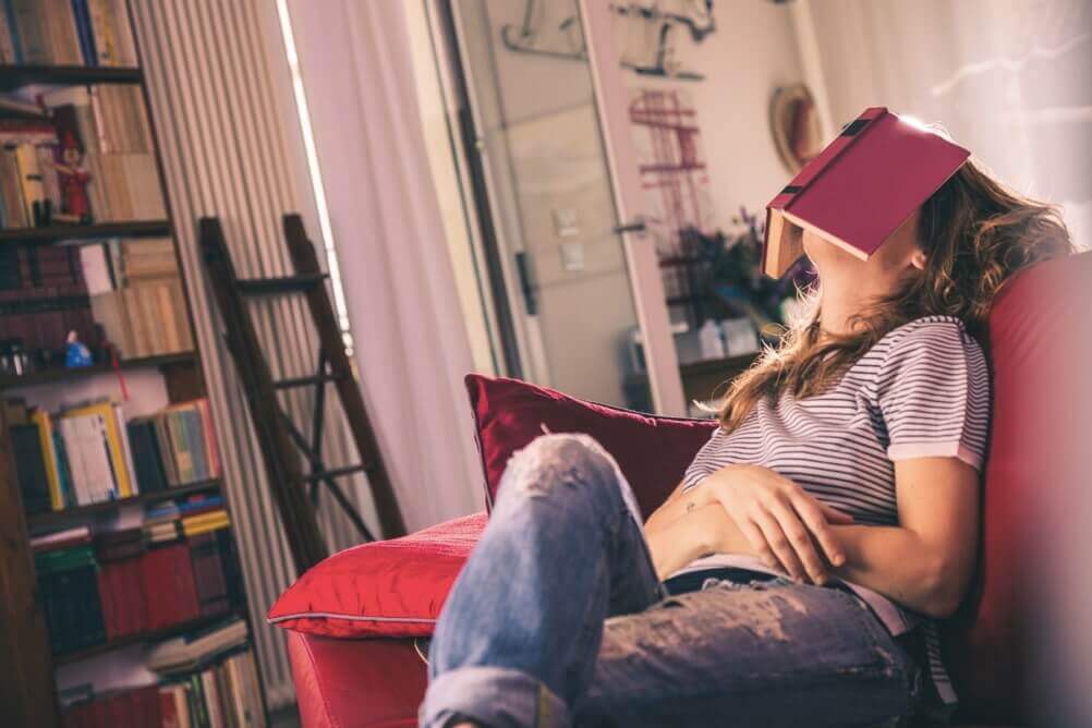 Woman sits on the sofa with a book on her face
