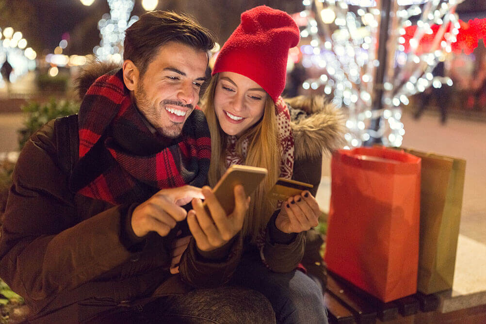 Junger Mann und junge Frau machen Weihnachtseinkäufe online