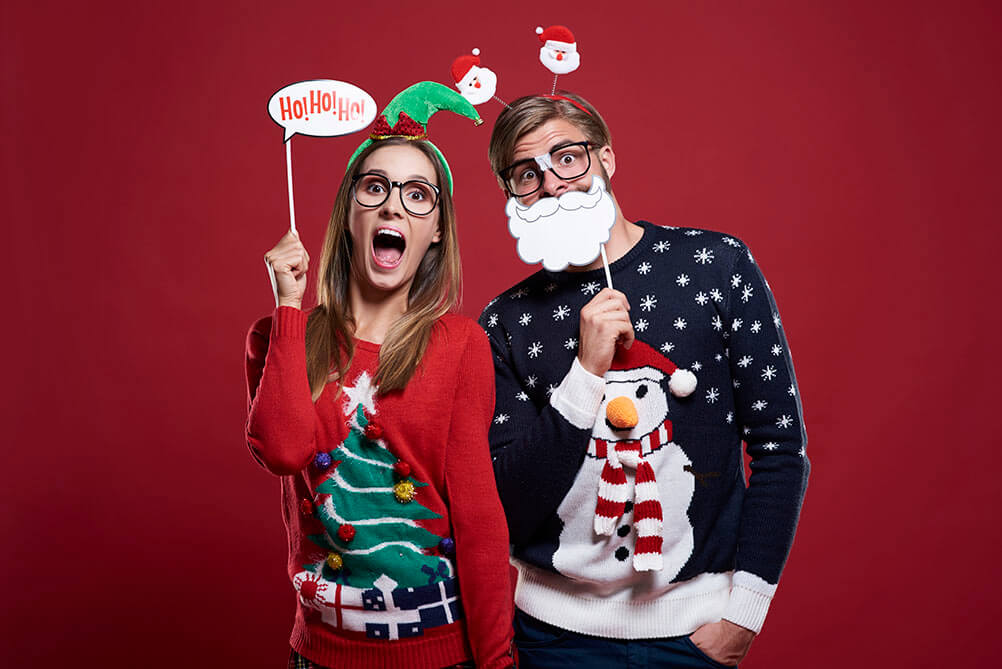 Couple dressed up in Christmas outfits against a red background