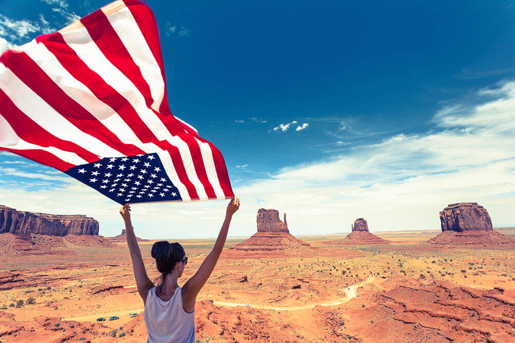 Uma mulher segurando uma bandeira americana no Gran Canyon - um dos lugares mais curiosos dos EUA