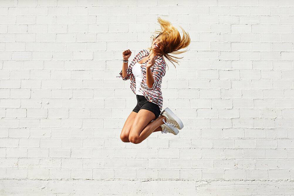 Uma mulher pulando de felicidade após atingir seus metas de ano novo