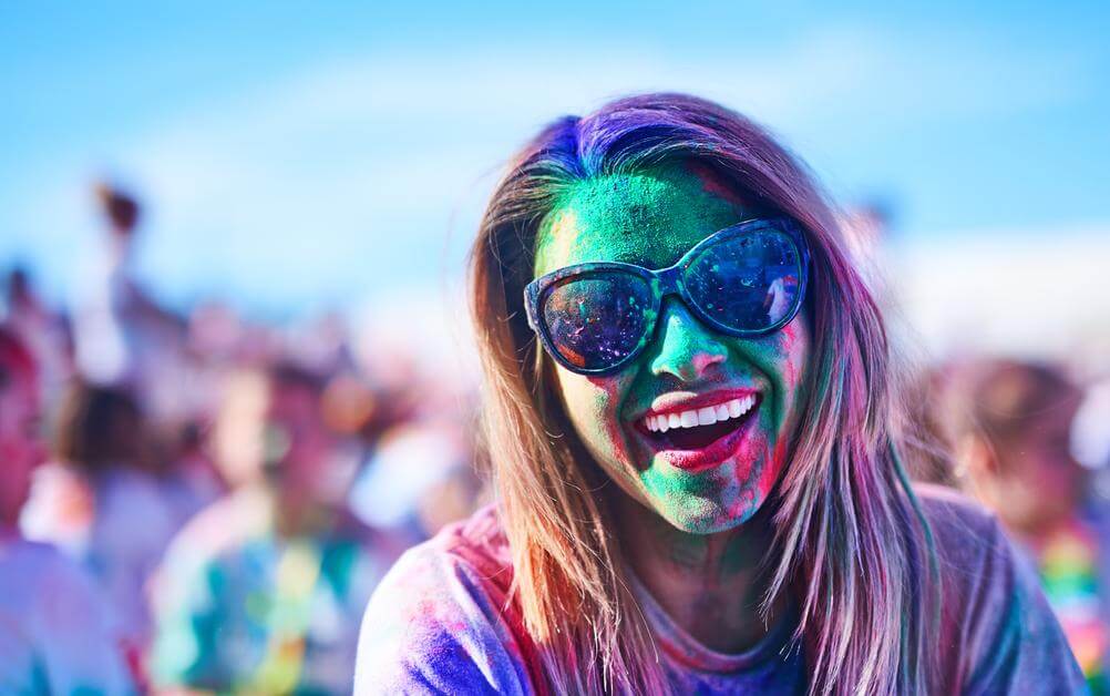 Mulher com cara coberta de tinta brinca em festival após ganhar na loteria