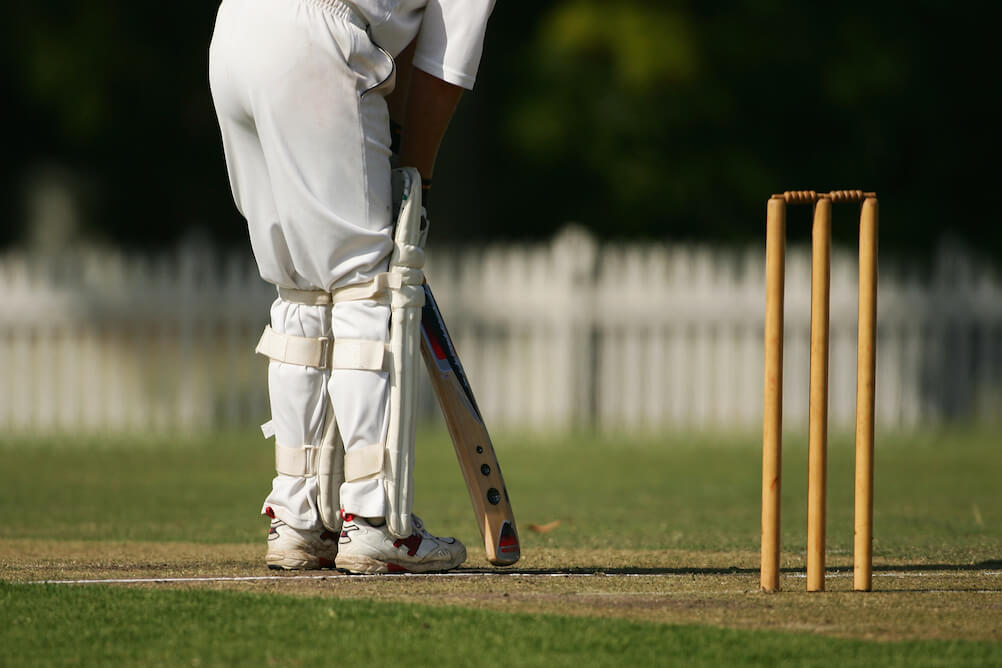 A shot of a man batting in cricket . We can see the wicket stumps. If you bet on cricket, you need to know these terms