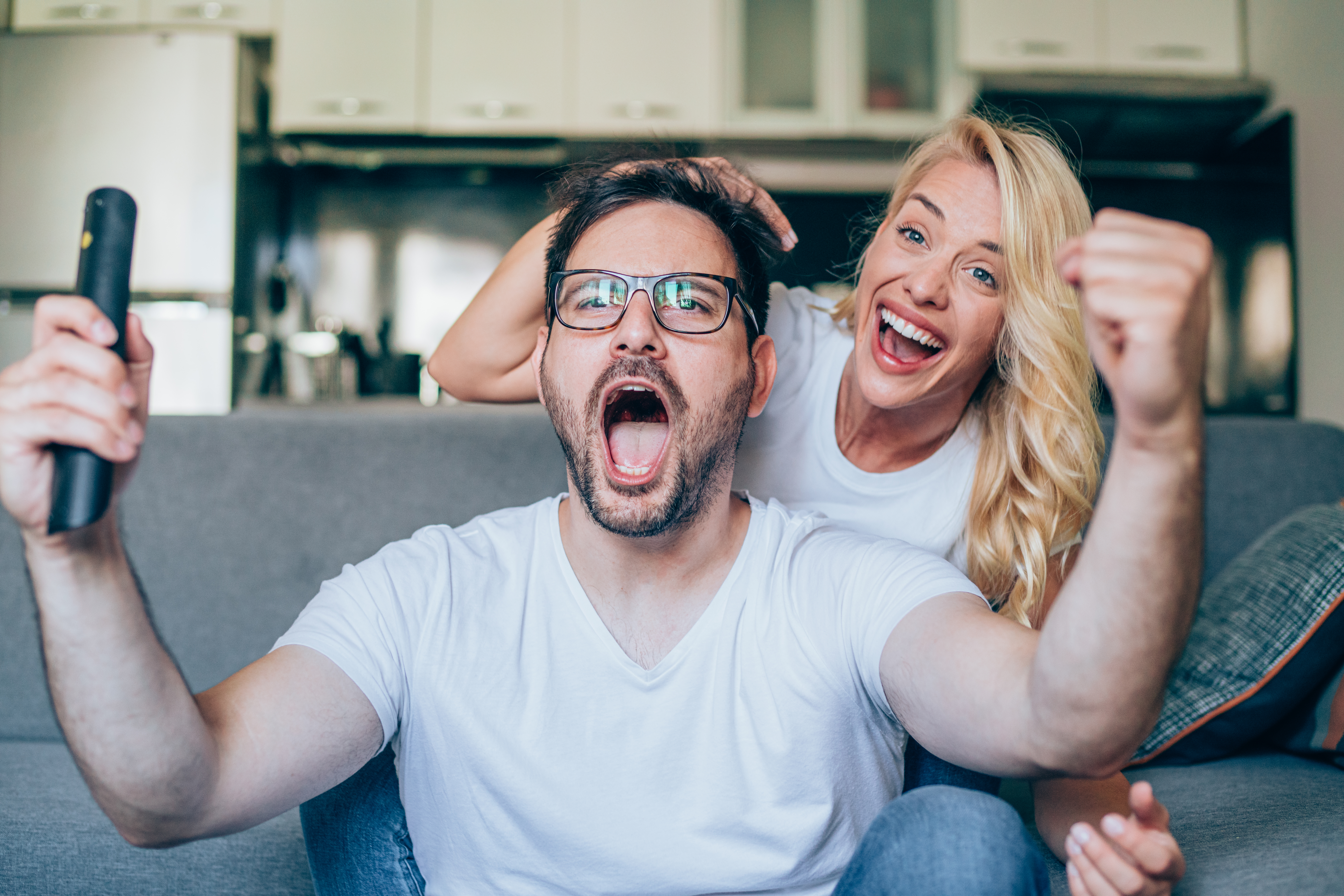 A man and a woman celebrating watching sports live as their in-play bet comes in.
